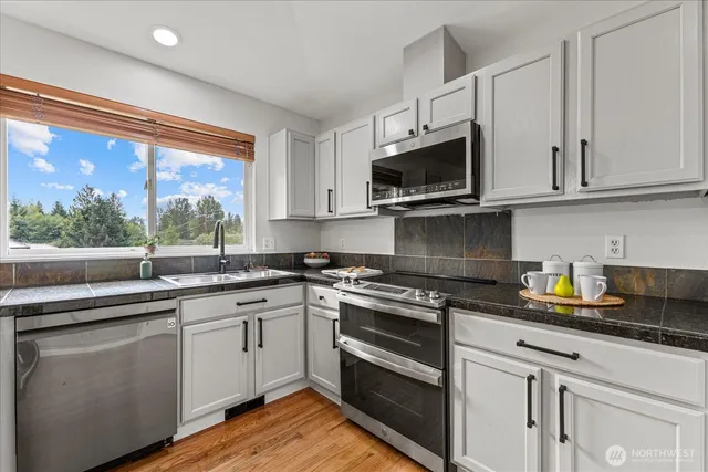 a kitchen with stainless steel appliances granite countertop a sink and cabinets with wooden floor