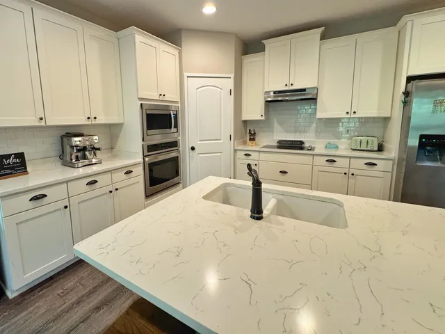 a kitchen with kitchen island granite countertop white cabinets white stainless steel appliances and sink