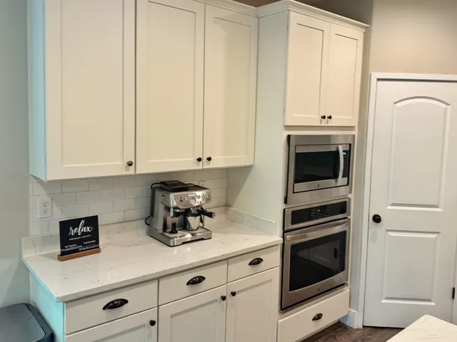 a kitchen with granite countertop white cabinets and white appliances