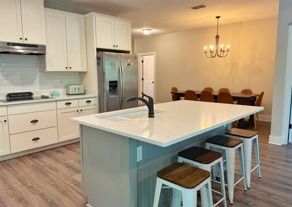 a kitchen with stainless steel appliances kitchen island a table chairs and a refrigerator