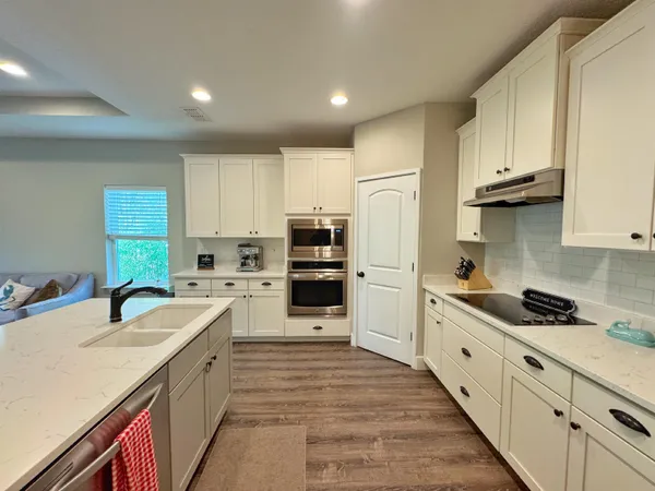 a kitchen with stainless steel appliances granite countertop a refrigerator a stove and white cabinets with wooden floor