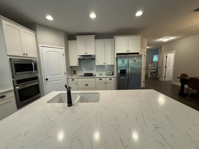 a large kitchen with stainless steel appliances a refrigerator a stove and a sink