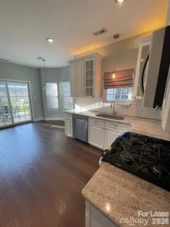 a kitchen with stainless steel appliances granite countertop a sink stove and wooden floor