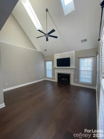 an empty room with windows fireplace and fans