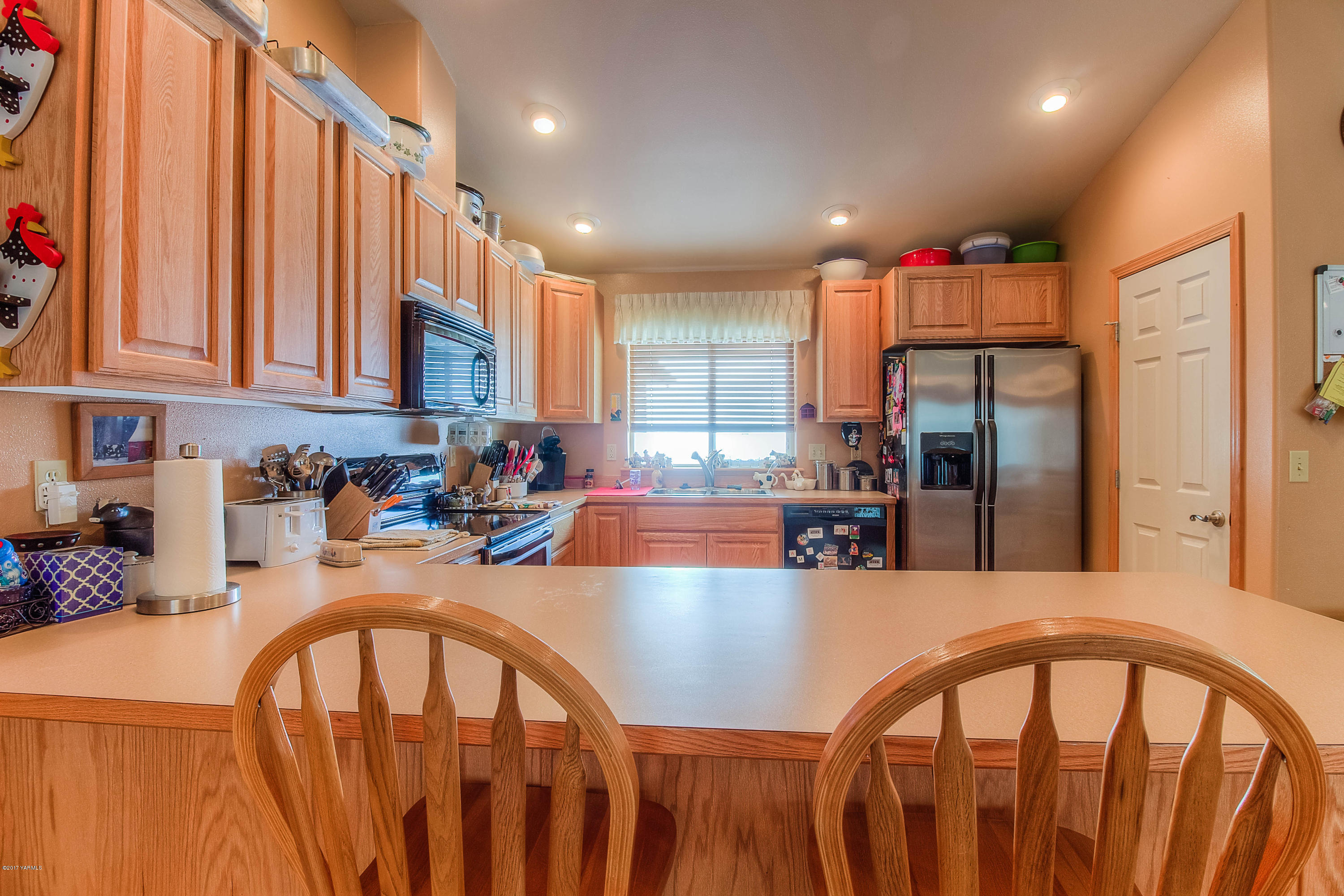 205 Beane Road Moxee, WA 98936 - Photo 11 of 28 a kitchen with stainless steel appliances granite countertop a dining table chairs sink refrigerator and cabinets