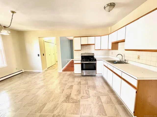 a large white kitchen with stainless steel appliances granite countertop a sink and cabinets