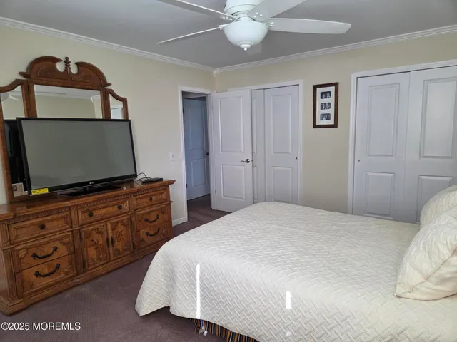 a bedroom with a bed and a flat tv screen on dresser
