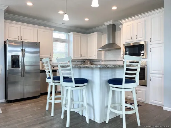 a kitchen with stainless steel appliances kitchen island granite countertop a table chairs microwave and cabinets