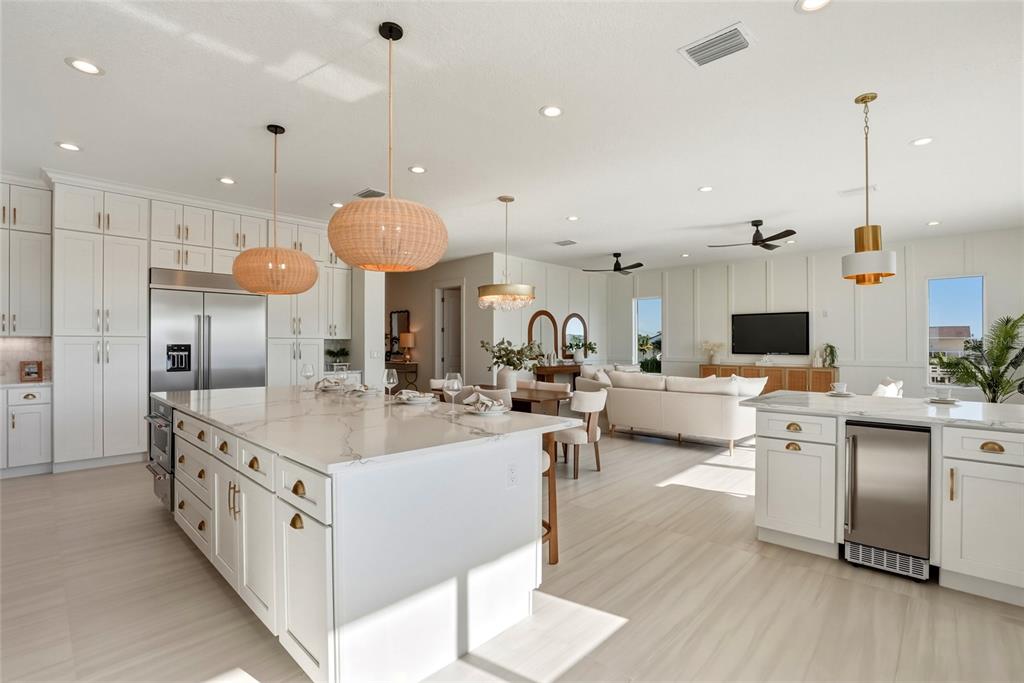 534 Crystal Drive Madeira Beach, FL 33708 - Photo 9 of 68 a large white kitchen with a large island in the center a sink stainless steel appliances and a chandelier