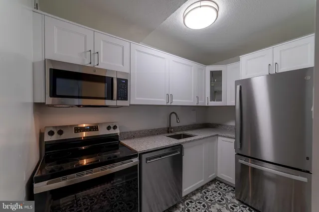 a kitchen with stainless steel appliances a refrigerator a stove top oven and cabinets