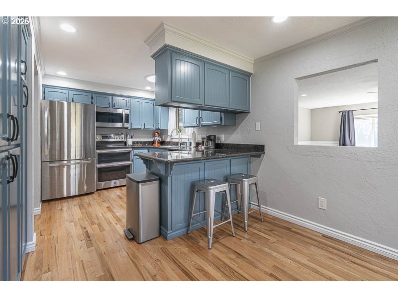 1216 Northeast Montgomery Place Albany, OR 97321 - Photo 13 of 47 a kitchen with kitchen island granite countertop wooden floors and stainless steel appliances
