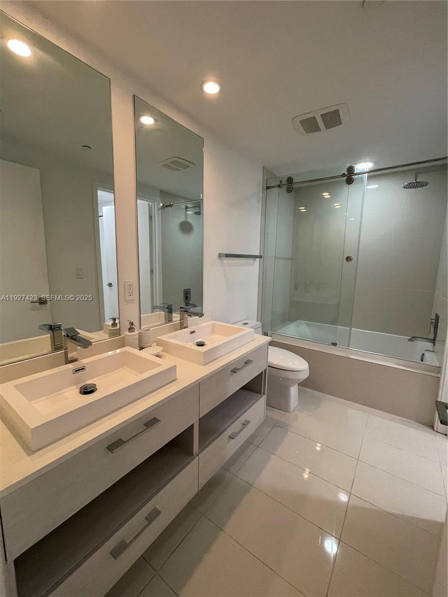 45 Southwest 9th Street, Unit 1407 Miami, FL 33130 - Photo 8 of 10 a bathroom with a double vanity sink toilet mirror and bathtub