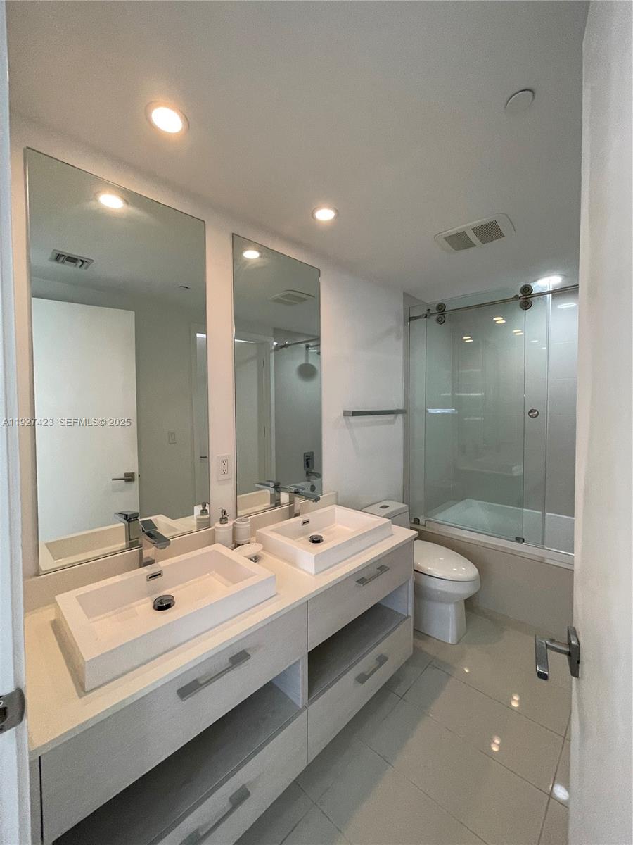 45 Southwest 9th Street, Unit 1407 Miami, FL 33130 - Photo 9 of 10 a bathroom with a double vanity sink toilet and shower