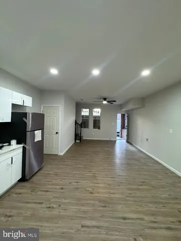 a view of an empty room with wooden floor and stairs