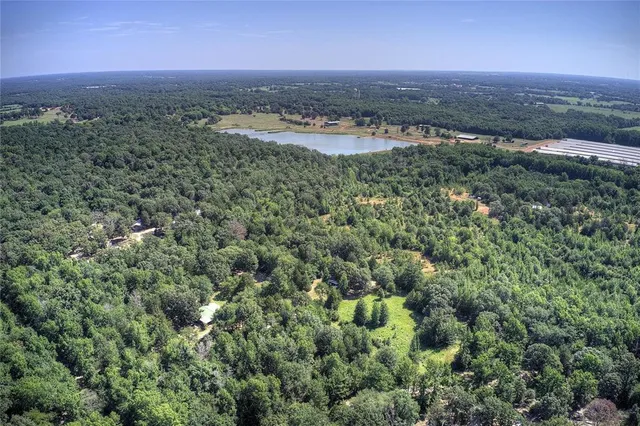 an aerial view of residential house with outdoor space and trees all around
