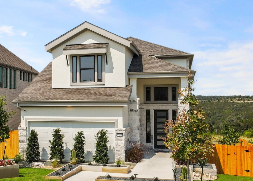View of front facade with a shingled roof, stucco siding, and stone siding