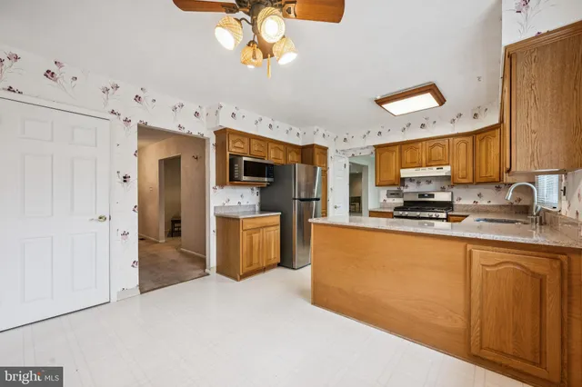 a large kitchen with stainless steel appliances granite countertop a stove refrigerator a sink dishwasher a microwave oven with cabinets and wooden floor