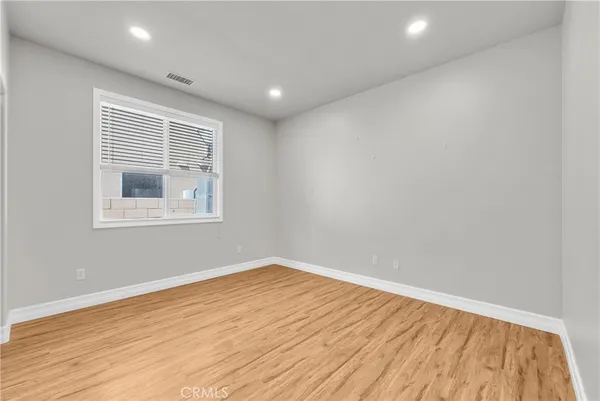 a view of empty room with wooden floor and fan
