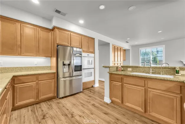 a kitchen with granite countertop stainless steel appliances a refrigerator cabinets and wooden floor