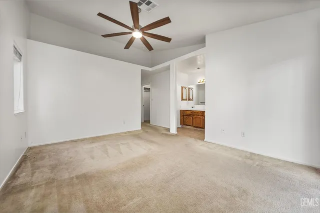 an empty room with chandelier fan and windows