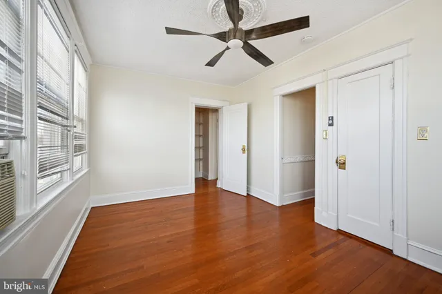 an empty room with wooden floor closet and windows