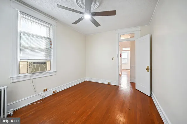 a view of an empty room with a window and wooden floor