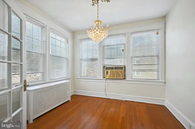 an empty room with wooden floor chandelier fan and windows