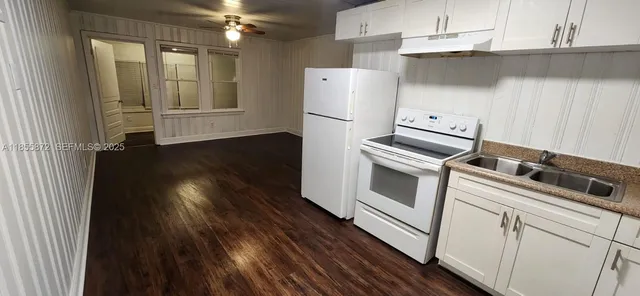 a kitchen with granite countertop white cabinets and refrigerator