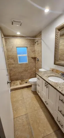 a bathroom with a granite countertop sink mirror vanity and toilet