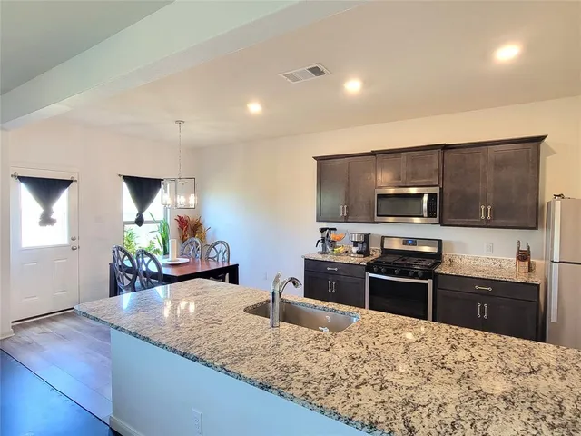 a kitchen with stainless steel appliances kitchen island granite countertop a sink stove and microwave