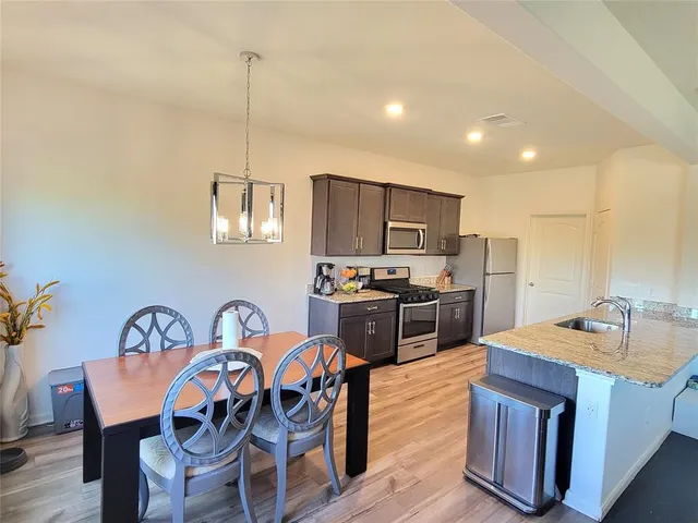 a kitchen with stainless steel appliances granite countertop a kitchen island hardwood floor sink and stove