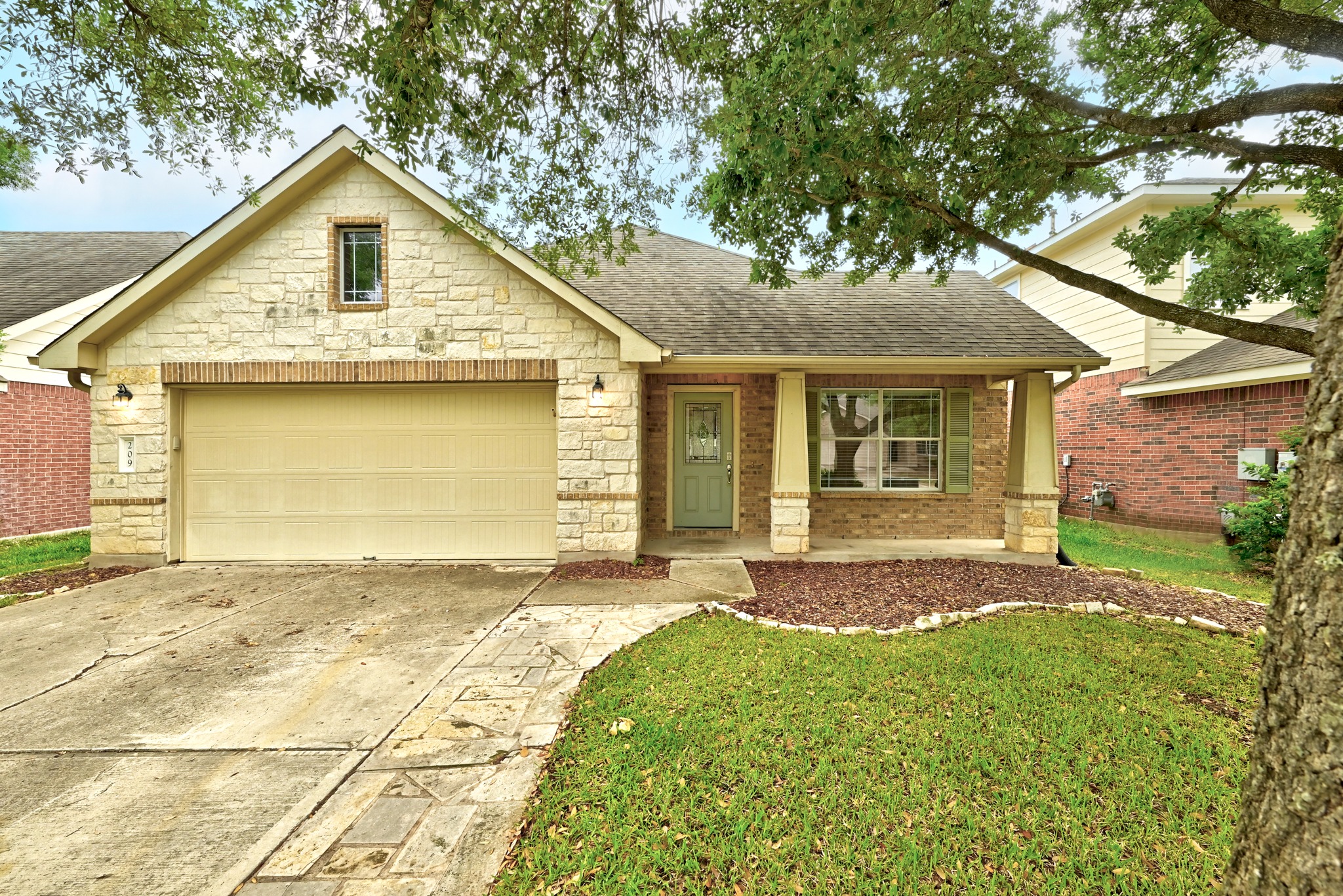 Stone veneer and brick façade with an attached garage, covered front porch, and decorative shutters