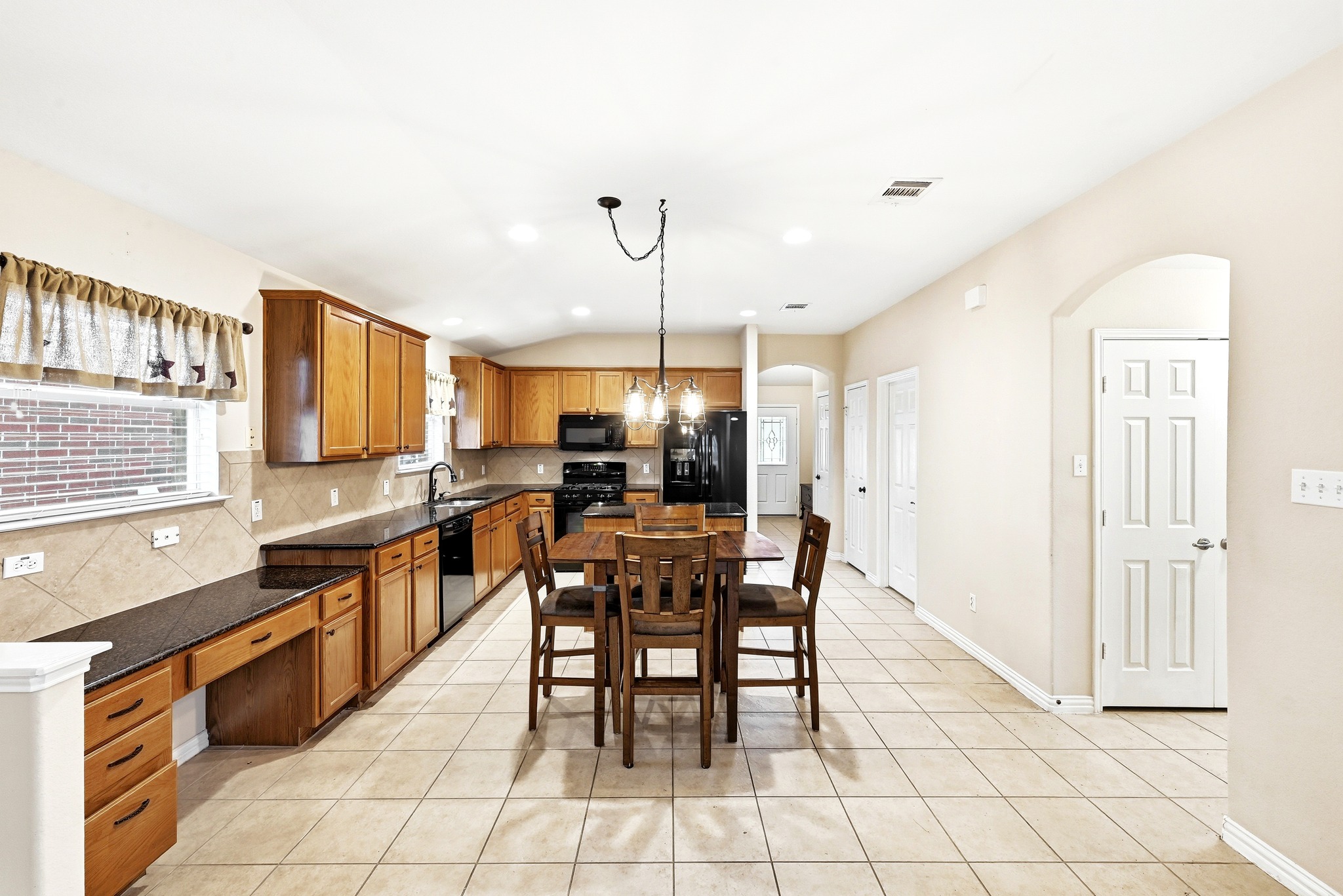 209 Calline Mayes Run Buda, TX 78610 - Photo 13 of 32 Open-concept kitchen and dining area featuring light wood cabinetry, black appliances, dark countertops, a tiled backsplash, and recessed lighting