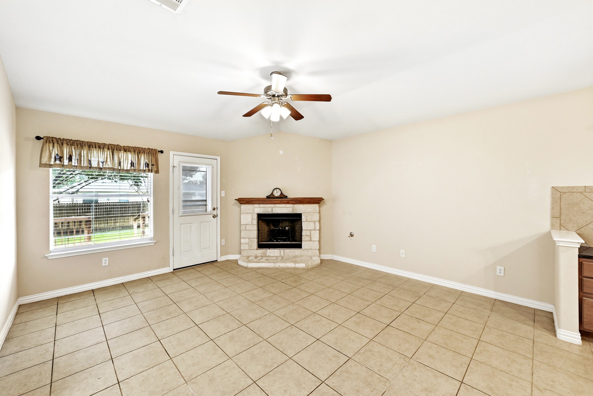 209 Calline Mayes Run Buda, TX 78610 - Photo 16 of 32 Neutral-toned tile flooring extends throughout this expansive room, featuring a corner fireplace with a stone surround and wood mantel