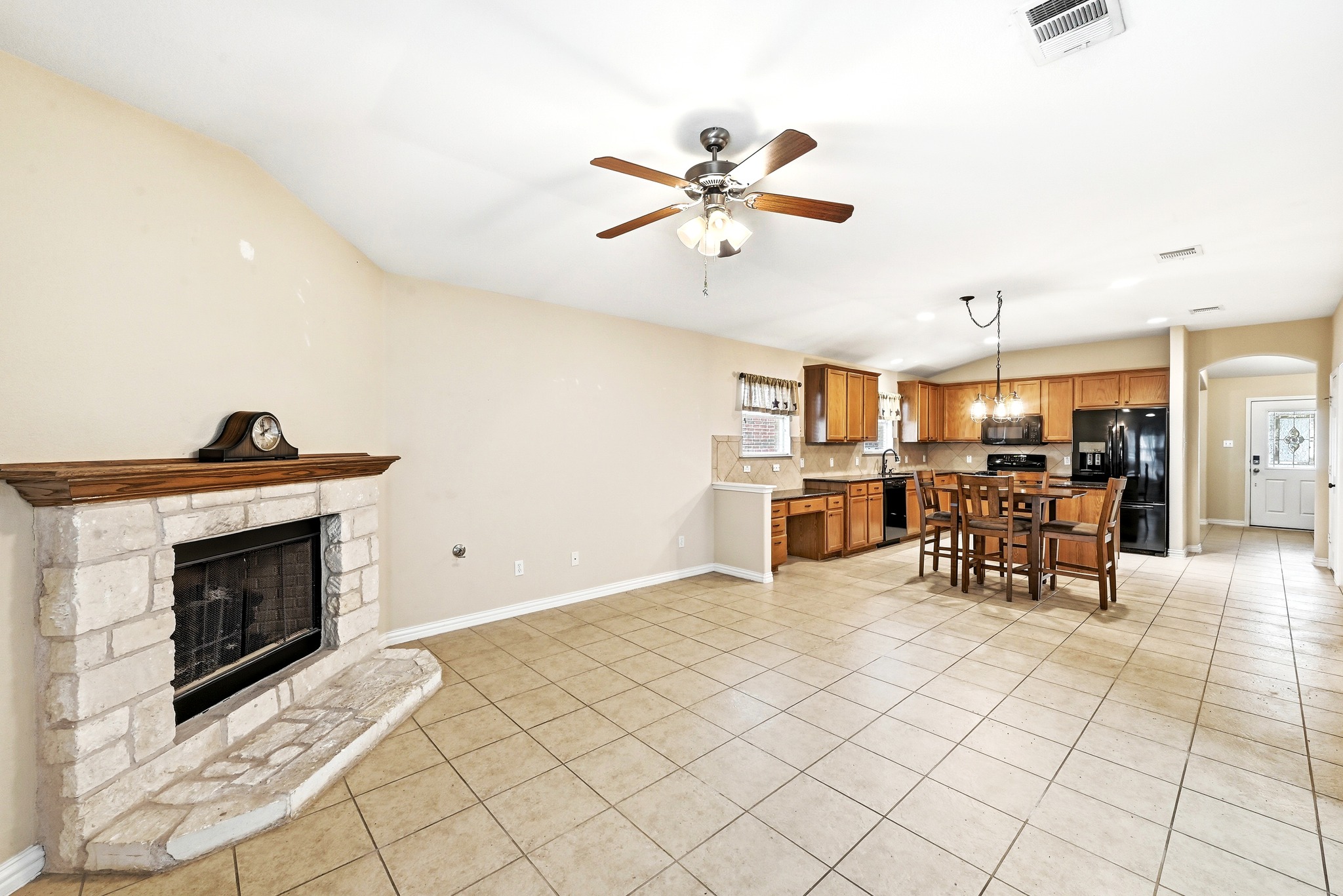209 Calline Mayes Run Buda, TX 78610 - Photo 18 of 32 Spacious open-concept living area featuring a stone fireplace with a wood mantle, tile flooring, and a ceiling fan