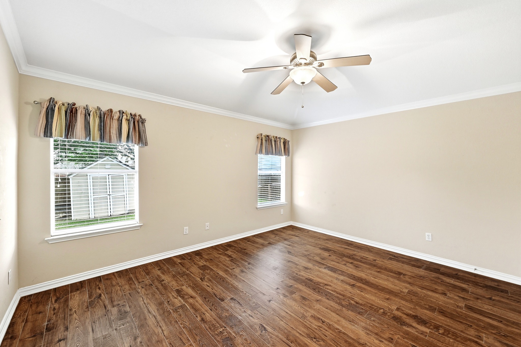 209 Calline Mayes Run Buda, TX 78610 - Photo 20 of 32 Spacious room featuring wood-finish flooring, two windows with blinds, a ceiling fan with integrated lighting, and crown molding