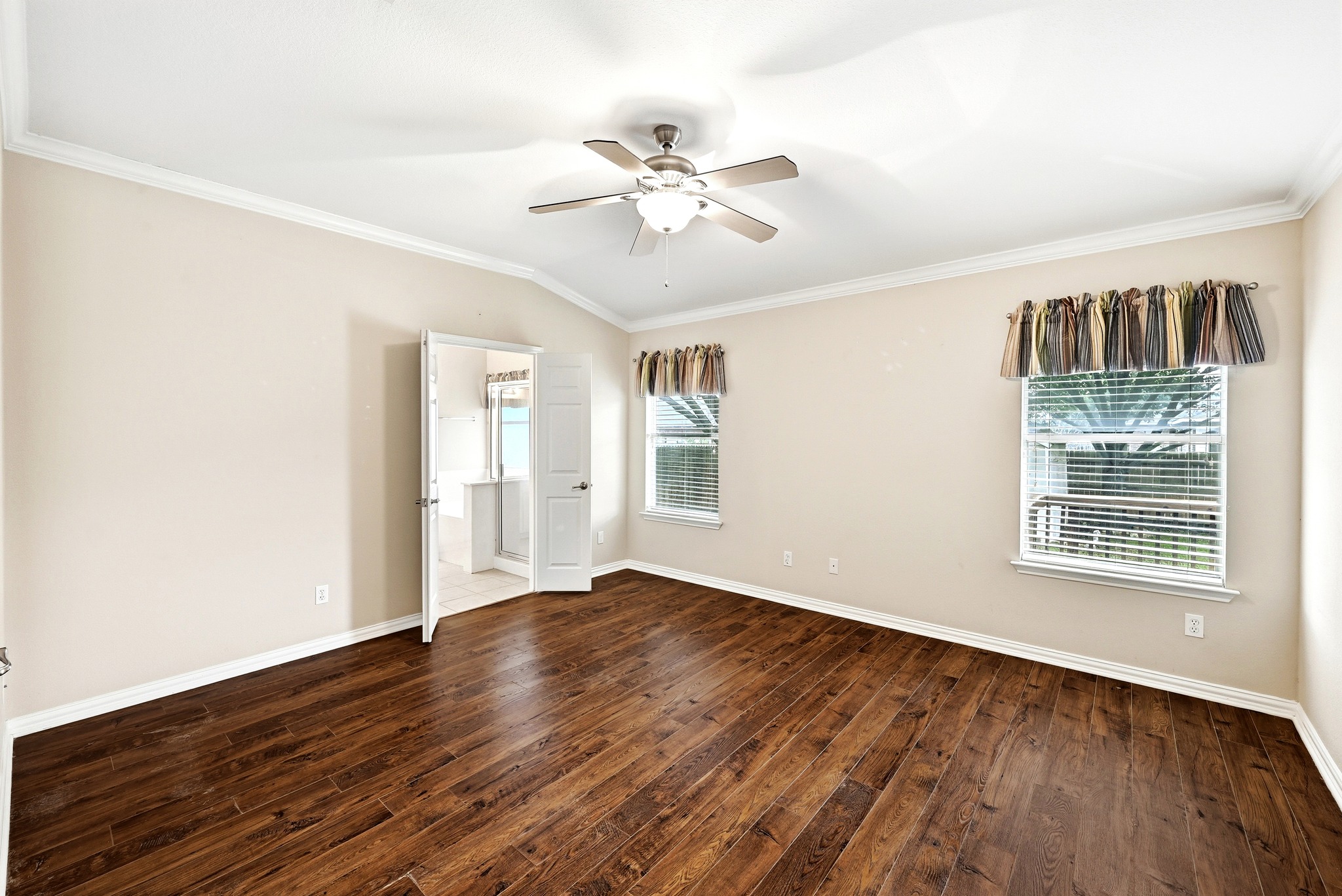 209 Calline Mayes Run Buda, TX 78610 - Photo 21 of 32 Spacious room featuring rich wood-finish flooring, a vaulted ceiling with a ceiling fan, crown molding, and two windows with blinds