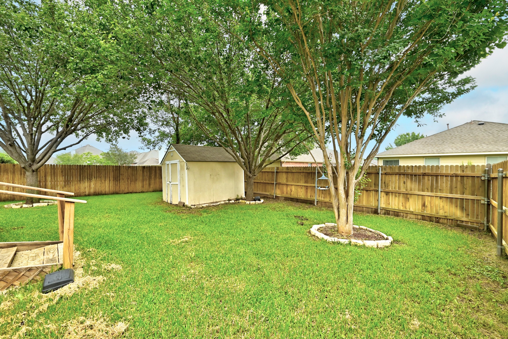 209 Calline Mayes Run Buda, TX 78610 - Photo 28 of 32 Spacious backyard featuring a wood privacy fence, mature trees, a storage shed, and a raised planter box