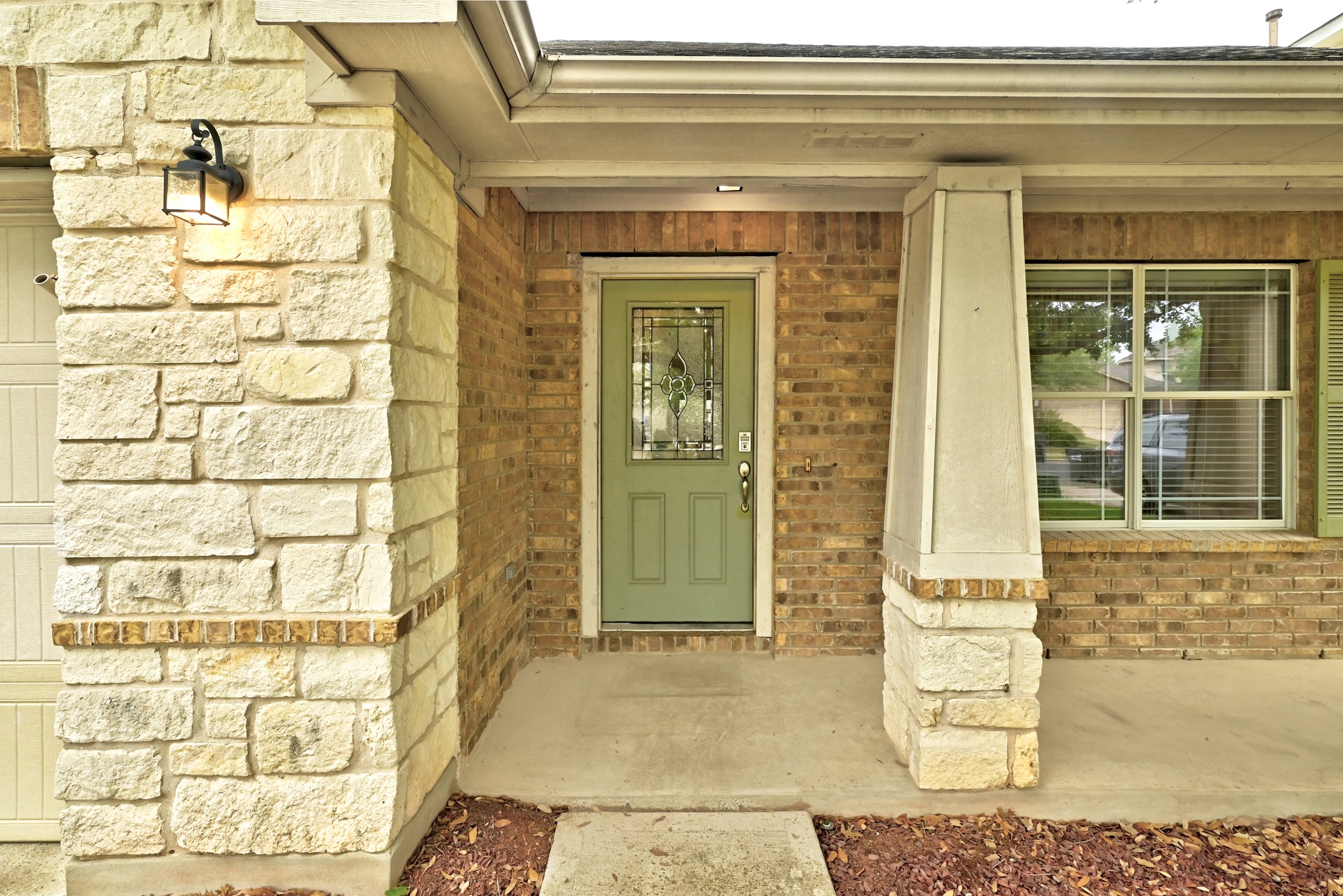 209 Calline Mayes Run Buda, TX 78610 - Photo 4 of 32 Front entry featuring a light green door with decorative glass inserts, brick and stone exterior, a covered porch, and a window with louvered shutters