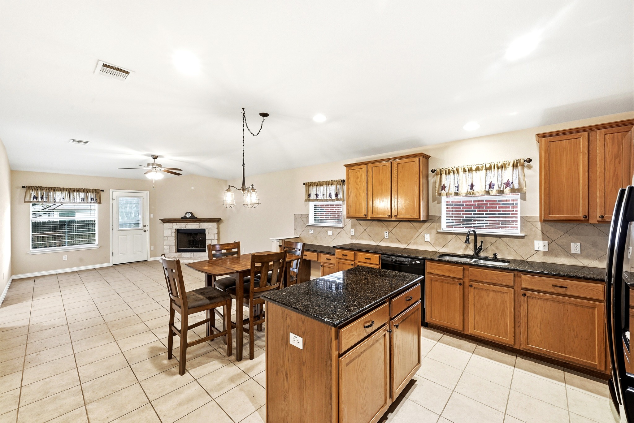 209 Calline Mayes Run Buda, TX 78610 - Photo 8 of 32 Open-concept kitchen featuring wood cabinetry, dark granite countertops, and a tiled backsplash