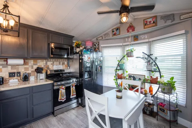 a kitchen with stainless steel appliances granite countertop a stove a sink dishwasher and a refrigerator with wooden floor