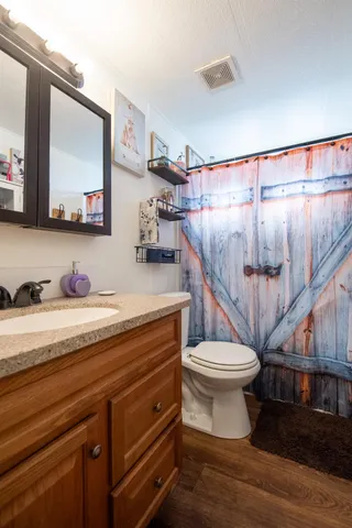 a bathroom with a granite countertop toilet sink and mirror