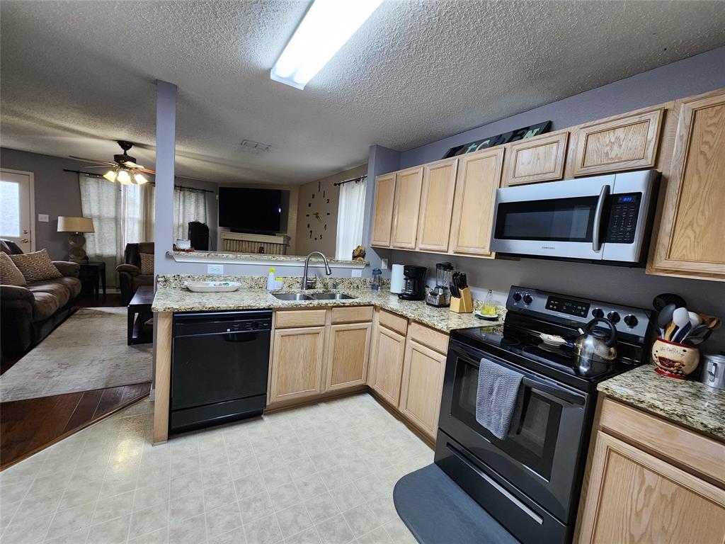 a kitchen with granite countertop a stove top oven a sink dishwasher and a microwave oven with cabinets