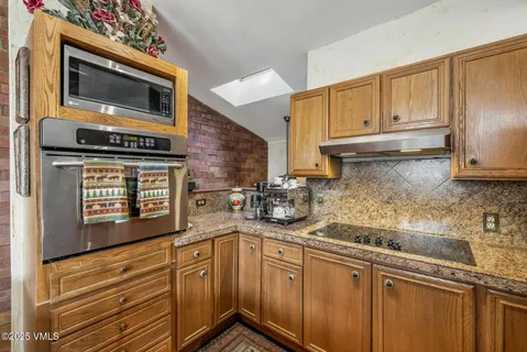 a kitchen with granite countertop stainless steel appliances a stove microwave and sink