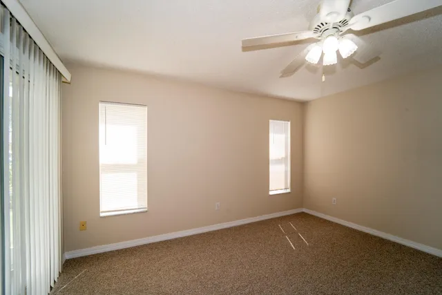 an empty room with windows and fan