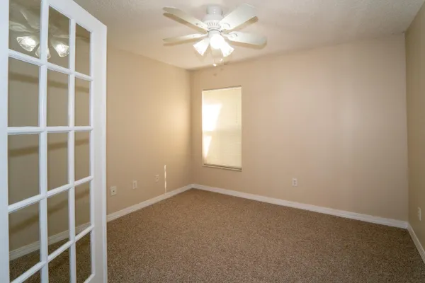 an empty room with a window and a fan