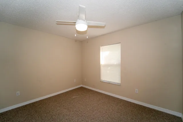 an empty room with a chandelier fan and window