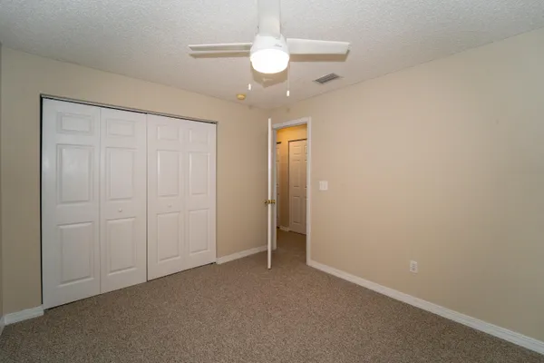 an empty room with a chandelier fan and a bathroom