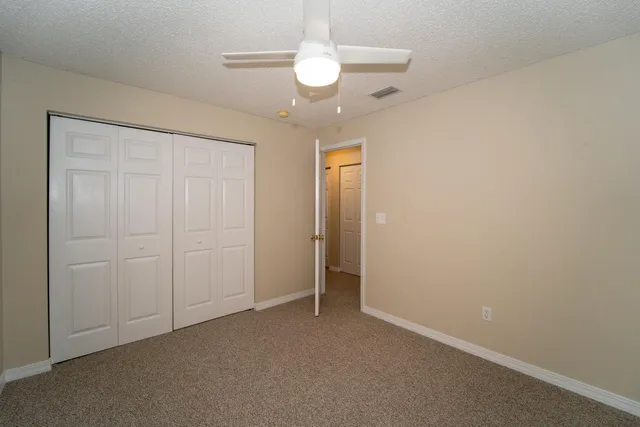 an empty room with a chandelier fan and a bathroom