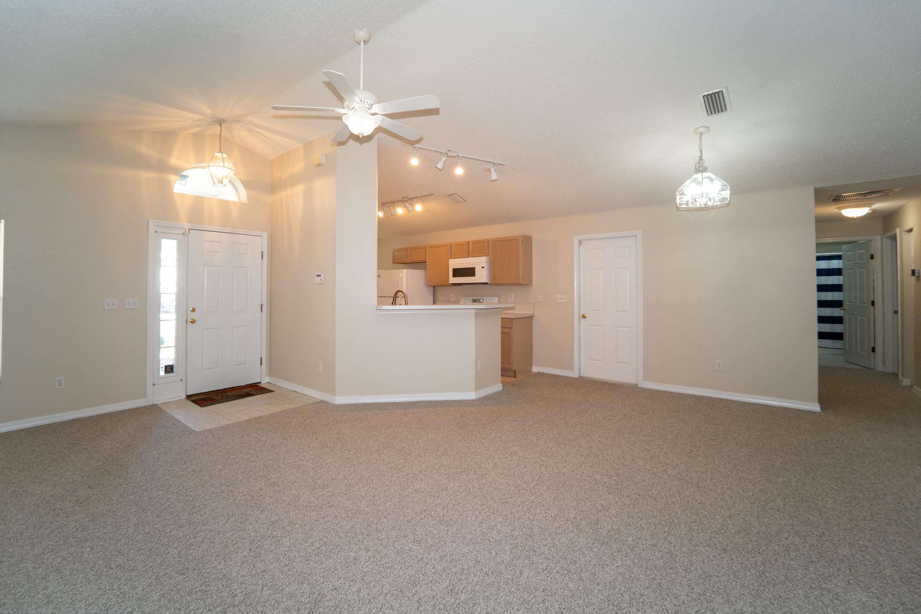 177 Marsh Island Circle St. Augustine, FL 32095 - Photo 10 of 33 an empty room with chandelier fan and windows